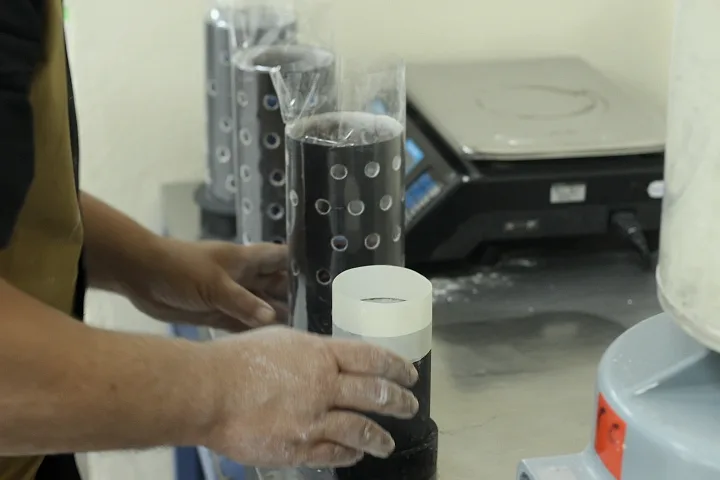 Mãos a preparar cilindros de microfusão para o revestimento